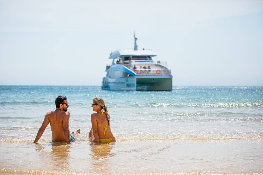 couple-sitting-on-the-beach-moreton-island-boat